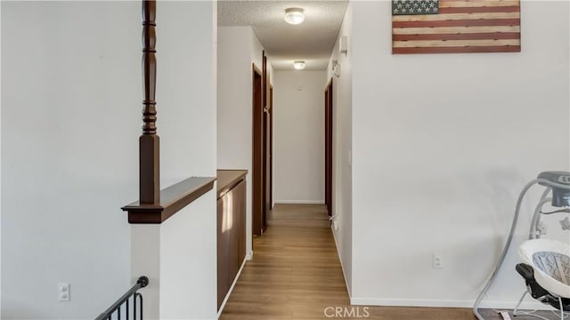 corridor with a textured ceiling and wood finished floors