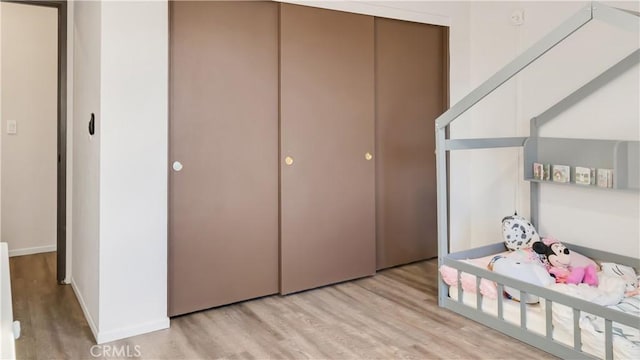 bedroom with a closet, baseboards, and light wood finished floors