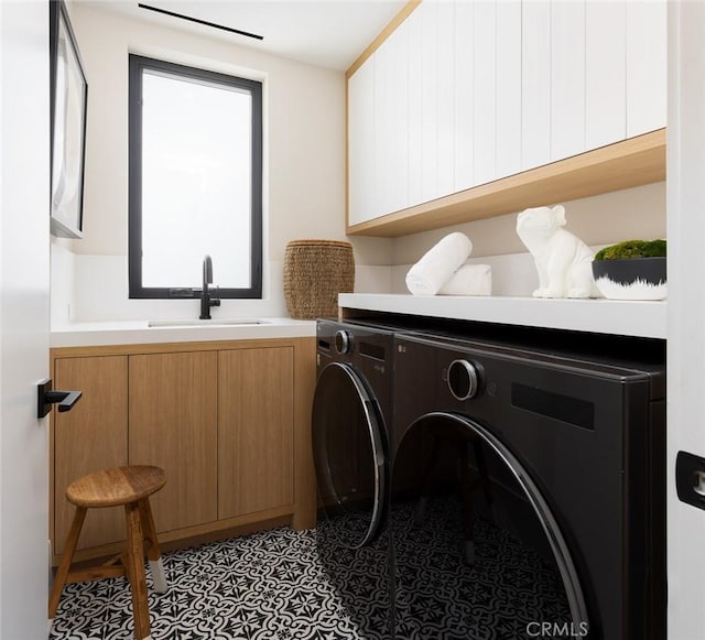 washroom featuring washer and dryer, cabinet space, and a sink