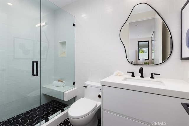 full bath featuring a stall shower, tile walls, toilet, and vanity