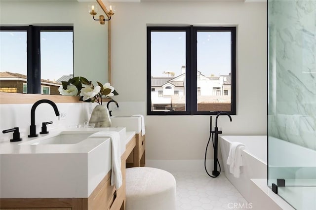 bathroom with a soaking tub, a notable chandelier, vanity, and tile patterned floors