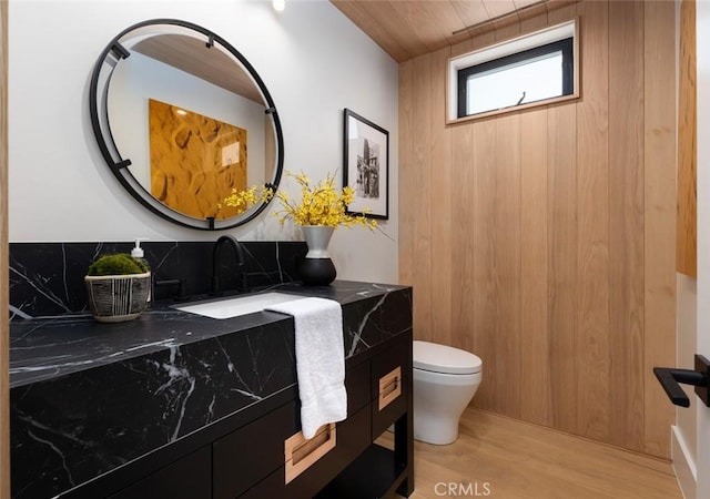 half bath featuring vanity, toilet, and wood finished floors