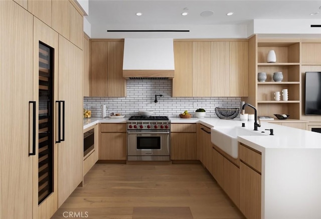 kitchen featuring premium range hood, light brown cabinetry, and appliances with stainless steel finishes