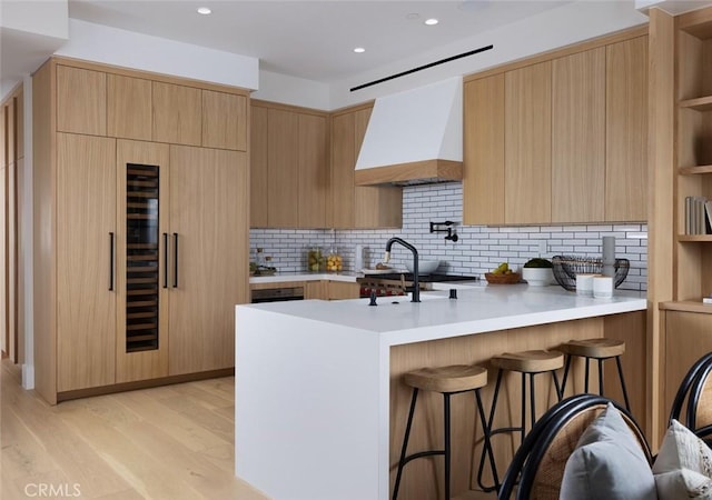 kitchen with modern cabinets, a peninsula, light countertops, premium range hood, and open shelves