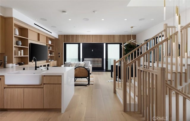 kitchen featuring light wood finished floors, modern cabinets, light countertops, open shelves, and a sink