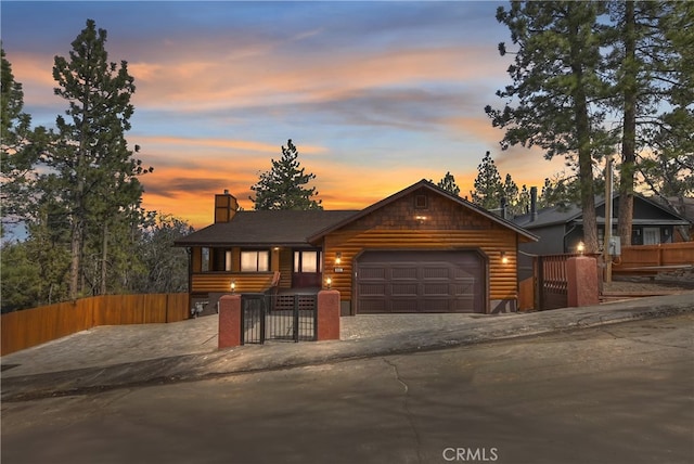 rustic home with a fenced front yard, faux log siding, a garage, and a gate