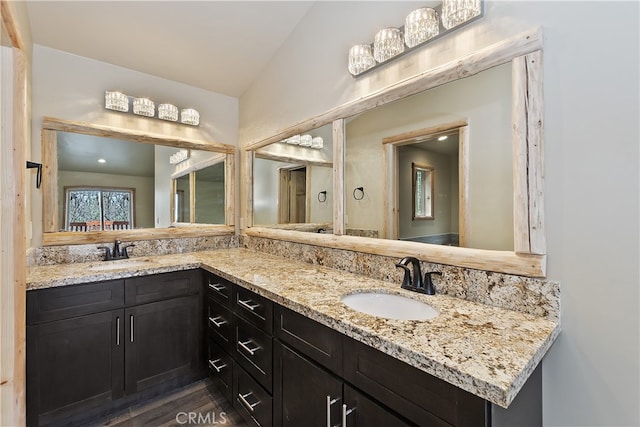 bathroom featuring double vanity, a sink, and lofted ceiling