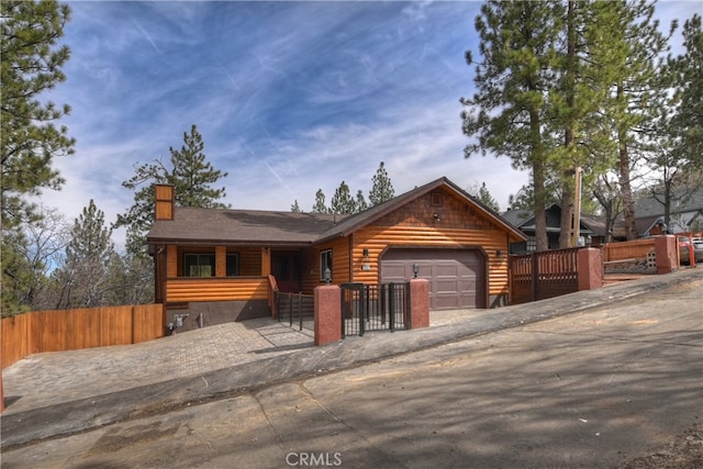 log-style house with a fenced front yard, an attached garage, and faux log siding