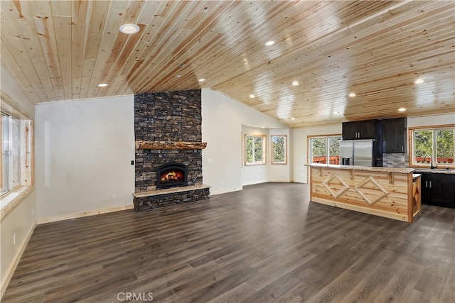 kitchen with stainless steel fridge, lofted ceiling, dark wood-style flooring, light countertops, and a fireplace