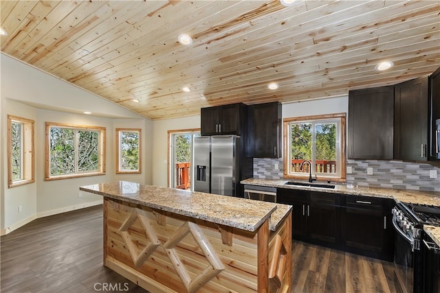 kitchen with dark wood finished floors, tasteful backsplash, appliances with stainless steel finishes, vaulted ceiling, and a sink