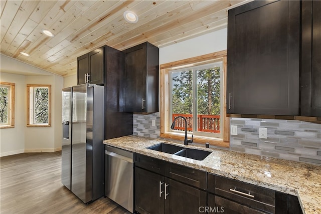 kitchen with baseboards, light stone counters, stainless steel appliances, light wood-type flooring, and a sink