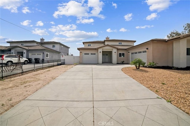 view of front of house with fence, driveway, an attached garage, and stucco siding