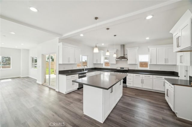 kitchen with dark wood finished floors, dark countertops, appliances with stainless steel finishes, wall chimney range hood, and beam ceiling