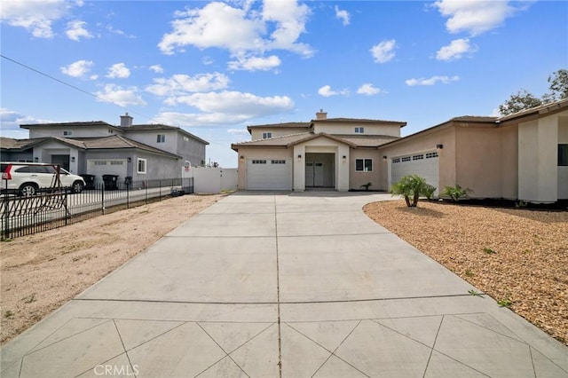 view of front of home with driveway, an attached garage, fence, and stucco siding