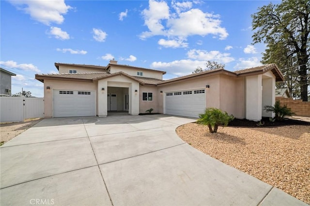 view of front facade with fence, a tiled roof, concrete driveway, stucco siding, and a garage