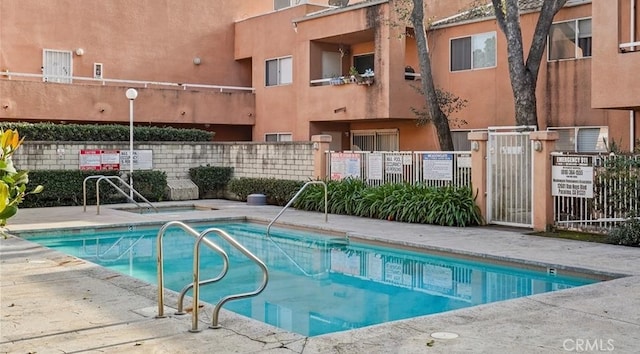 view of swimming pool featuring fence and a hot tub