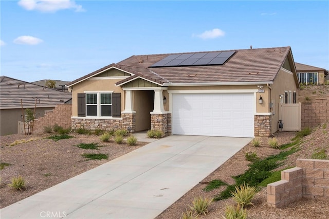 view of front of home featuring an attached garage, solar panels, fence, stone siding, and driveway