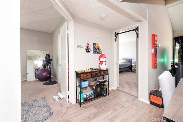 hallway featuring carpet flooring, a textured ceiling, and wood finished floors