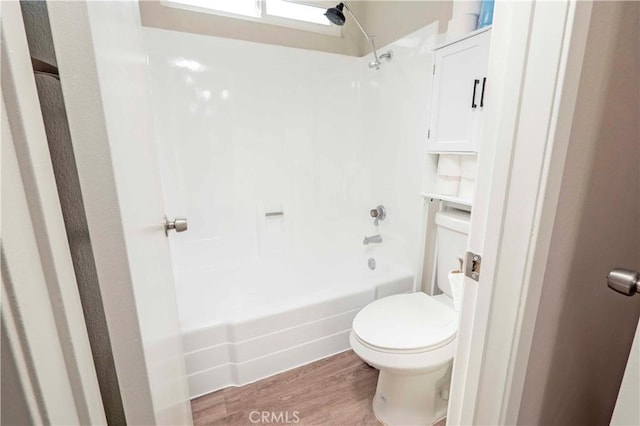 full bath with bathing tub / shower combination, toilet, and wood finished floors