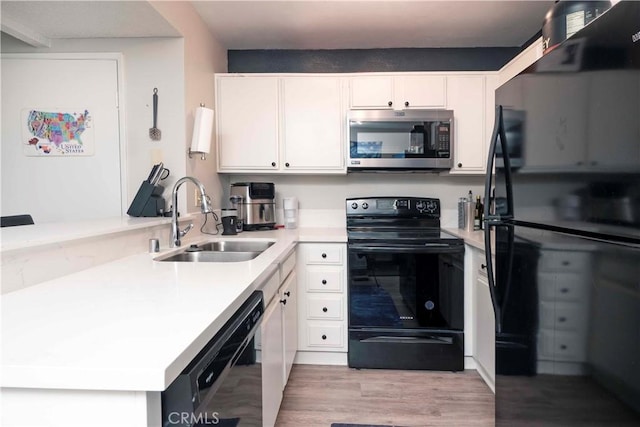 kitchen with light countertops, light wood-style flooring, white cabinetry, a sink, and black appliances