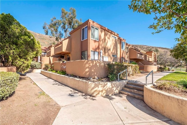 view of front of property with fence, a mountain view, and stucco siding