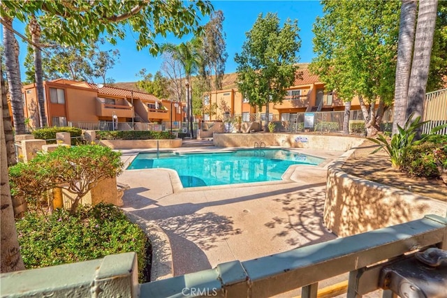 community pool with a residential view, fence, and a patio