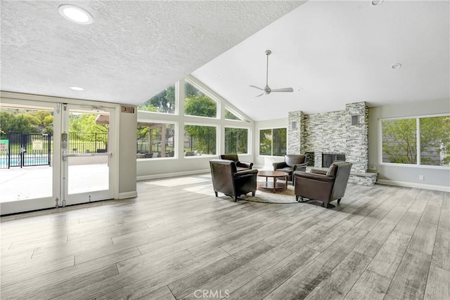 sunroom with lofted ceiling, plenty of natural light, a fireplace, and a ceiling fan