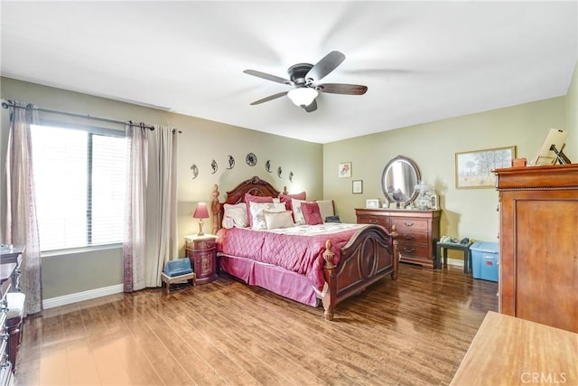bedroom with a ceiling fan, baseboards, and wood finished floors