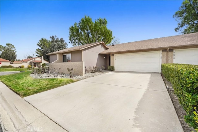 ranch-style house featuring concrete driveway, an attached garage, and stucco siding