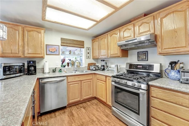 kitchen with under cabinet range hood, light brown cabinets, stainless steel appliances, and a sink