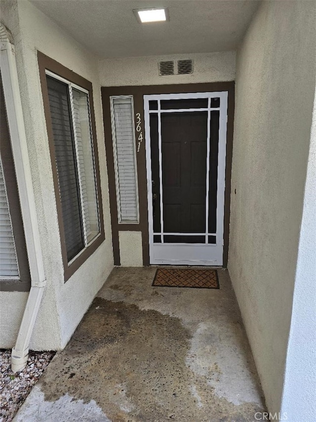 doorway to property with visible vents and stucco siding