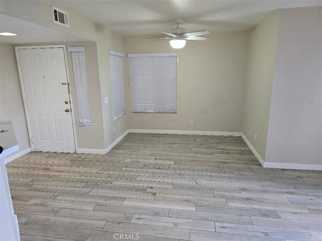 foyer featuring baseboards, wood finished floors, visible vents, and ceiling fan