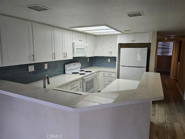 kitchen featuring backsplash, wood finished floors, white cabinetry, white appliances, and a peninsula