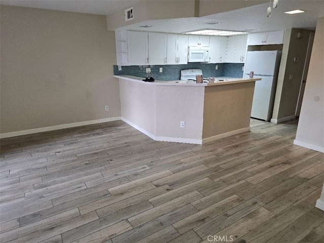 kitchen with white appliances, wood finished floors, visible vents, a peninsula, and white cabinetry