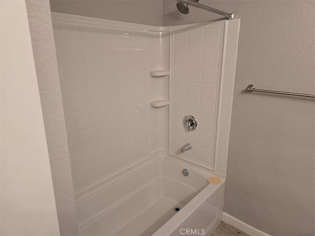 full bath with shower / bath combination, baseboards, and a textured wall