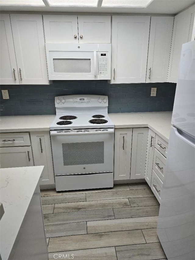 kitchen featuring light stone counters, tasteful backsplash, white appliances, white cabinets, and wood tiled floor