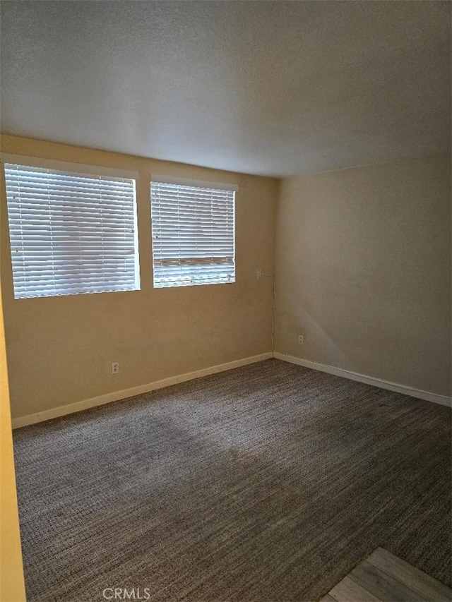 carpeted spare room featuring baseboards