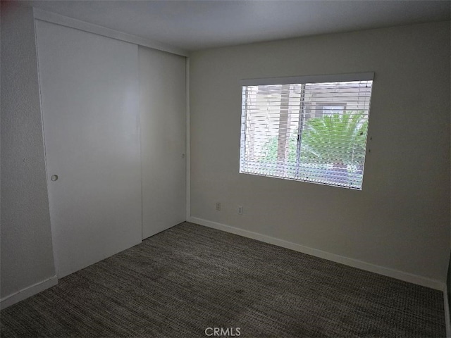 spare room with baseboards and carpet floors