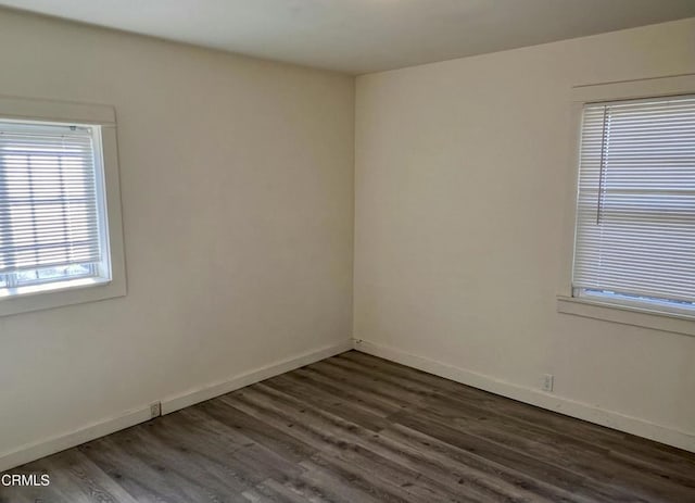 spare room featuring dark wood finished floors and baseboards