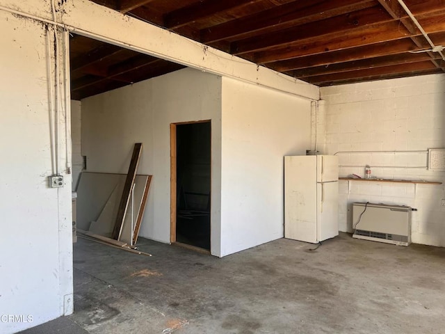 basement with freestanding refrigerator and concrete block wall