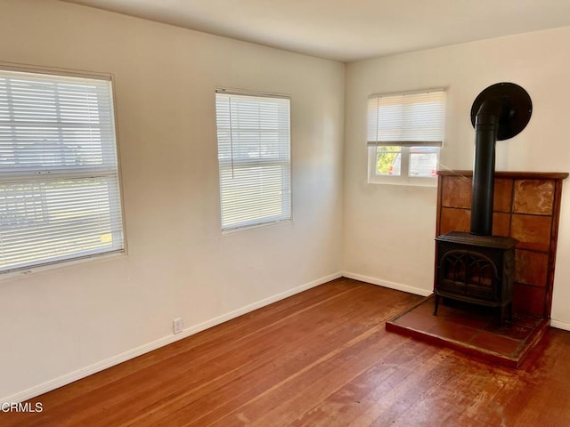 unfurnished living room with a wood stove, baseboards, and wood finished floors