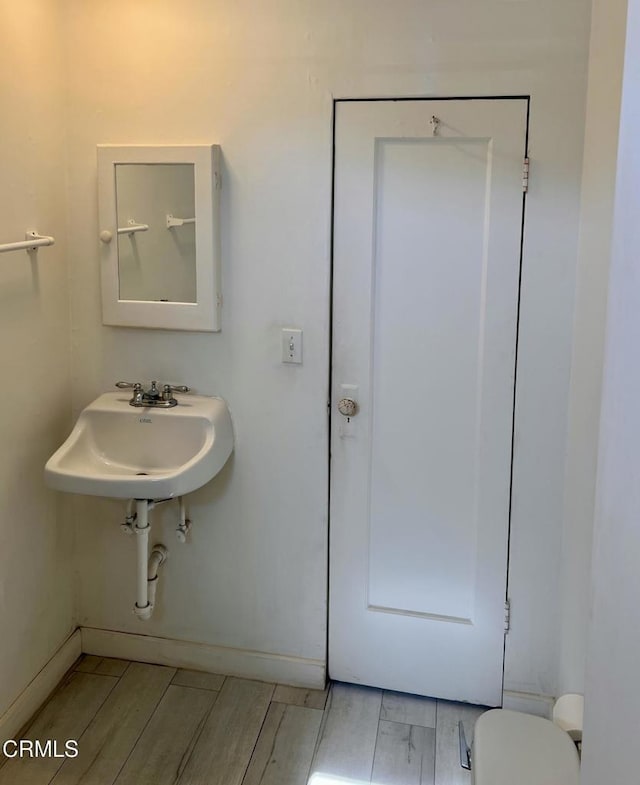 bathroom with wood finish floors, a sink, toilet, and baseboards