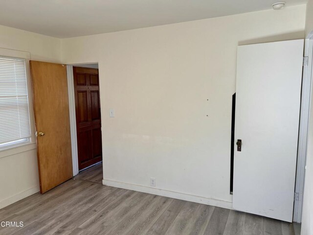unfurnished room with baseboards and light wood-type flooring