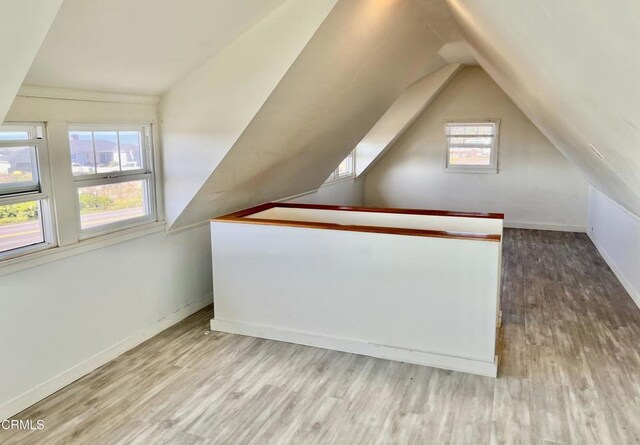 additional living space with baseboards, vaulted ceiling, and wood finished floors