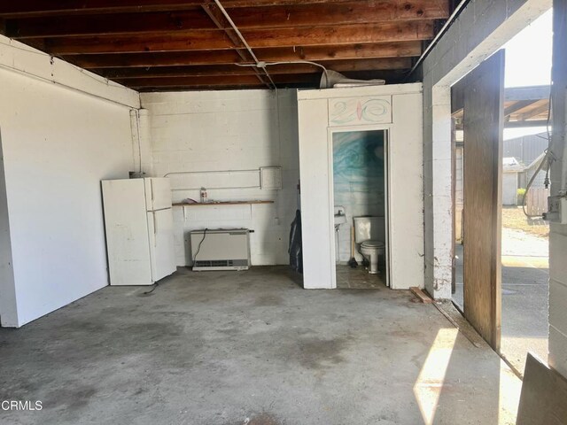 basement with concrete block wall and freestanding refrigerator