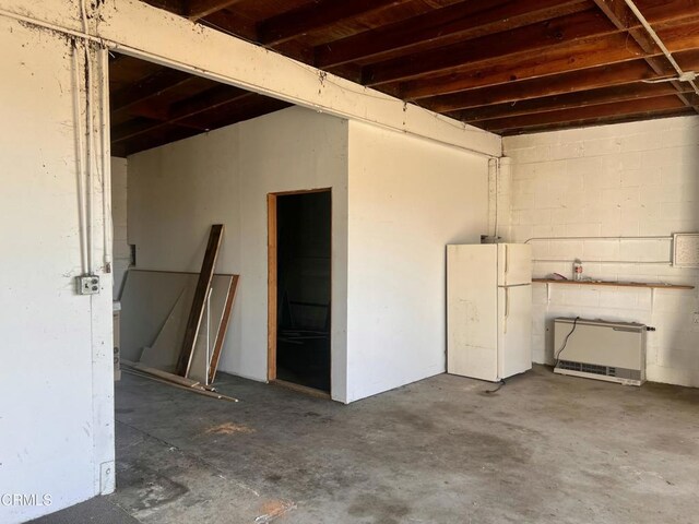 garage featuring concrete block wall and freestanding refrigerator