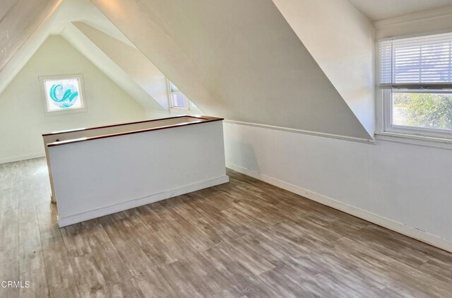 additional living space with baseboards, vaulted ceiling, and wood finished floors
