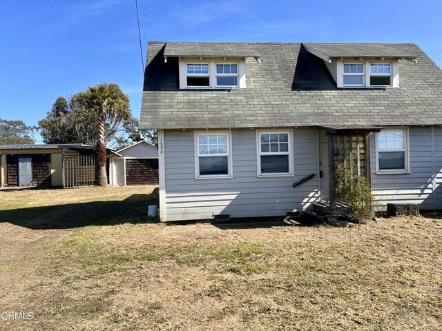 back of house with a shingled roof and a yard