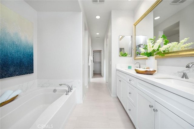 full bathroom featuring double vanity, a sink, a bath, and recessed lighting