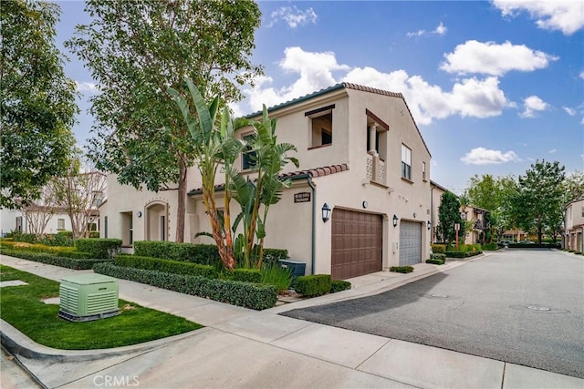 mediterranean / spanish-style house featuring a tile roof, an attached garage, and stucco siding